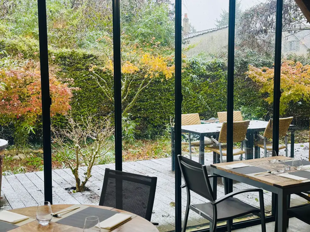 La véranda du Sushikai en automne, tables dressées face au jardin aux feuillages rouges et dorés