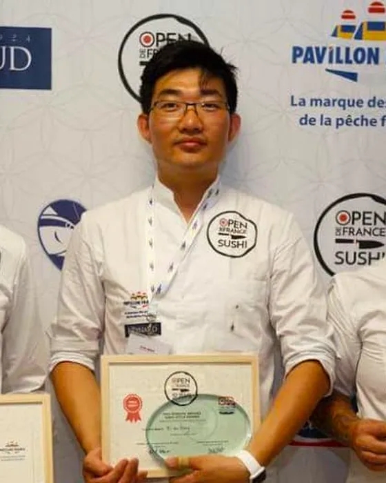 Le chef Wang, diplôme et trophée en main, lors de la remise des prix de l’Open de France de sushi