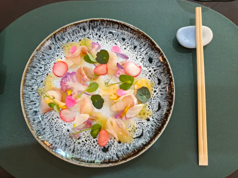 Assiette de sashimis de poisson blanc, radis et fleurs comestibles